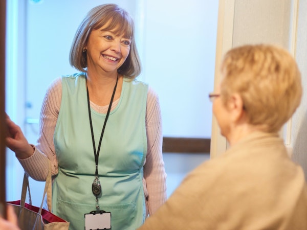 Older woman letting in her home care worker