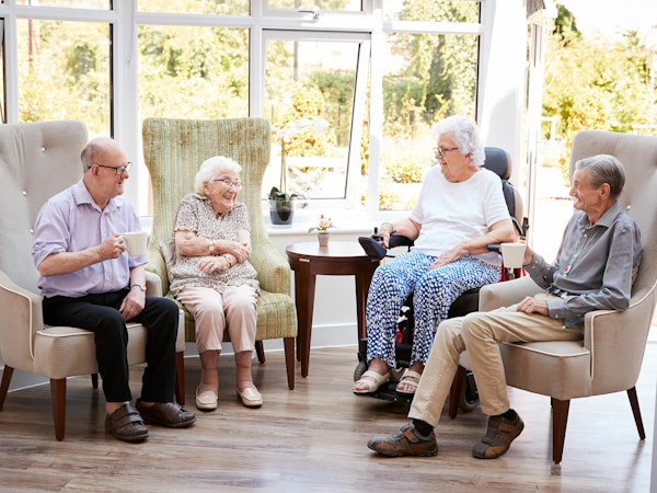 Group of aged care residents sitting together smiling and talking (Source: Shutterstock)