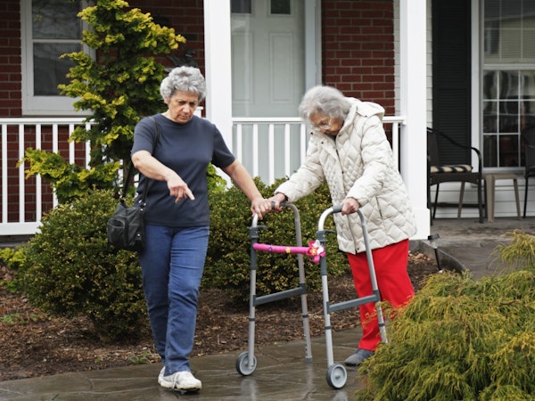 Older person getting assistance traversing wet walkway