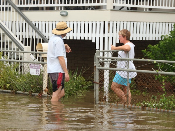 Older couple talking outside their house that has been affected by the floods